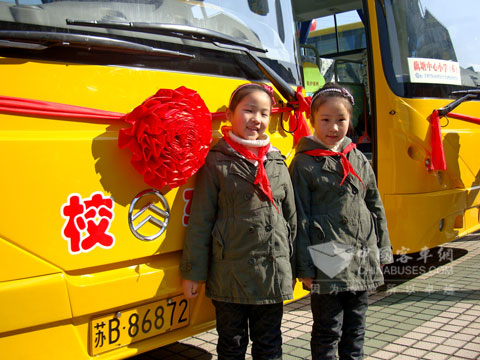 潘氏双胞胎姐妹与在金旅校车前合影留念