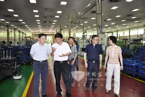 重庆市经信委副主任杨孝荣（左一）在綦齿传动公司参观生产现场